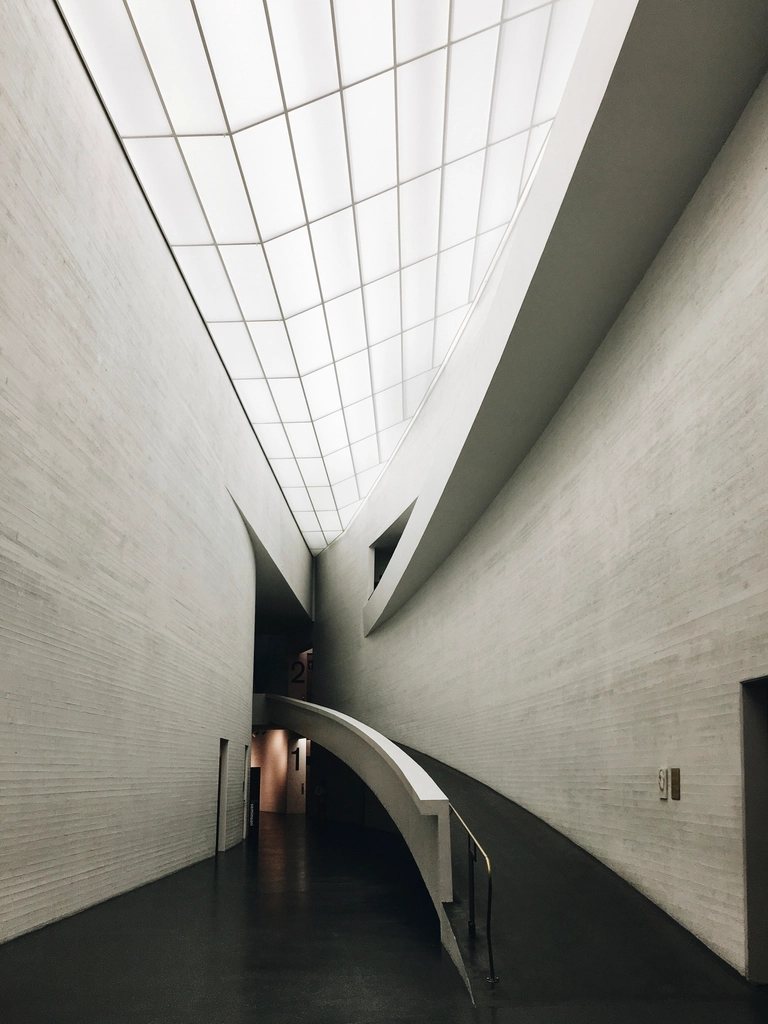 Curved concrete corridor under a skylight
