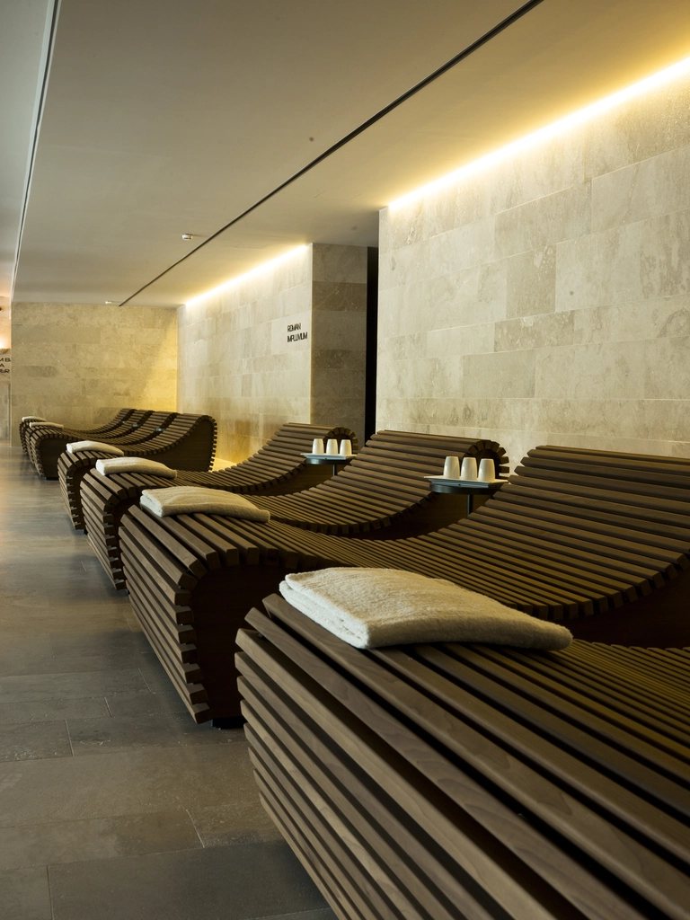 Timber loungers along a lit stone wall